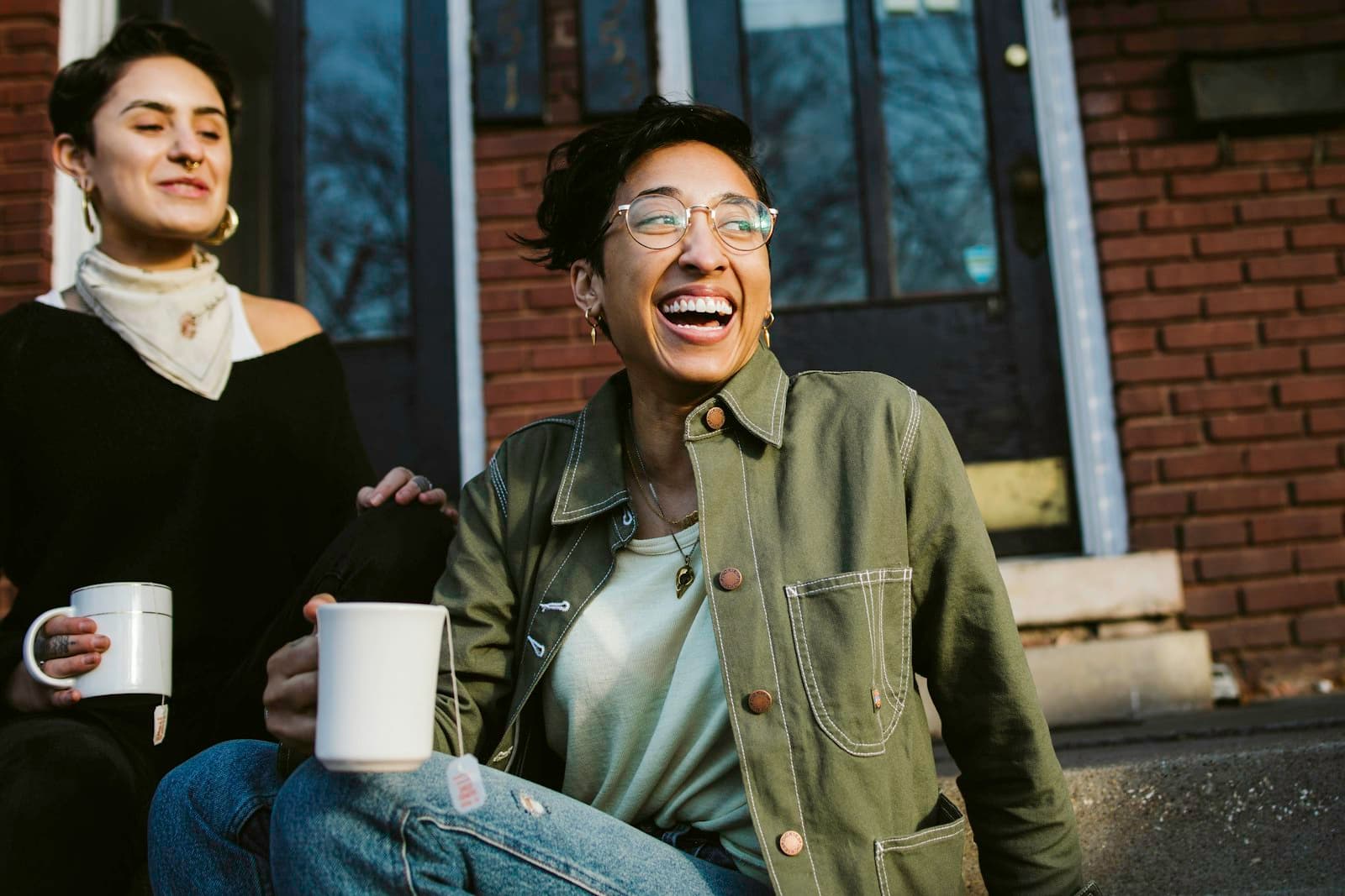 Two neighbors laughing over coffee outside